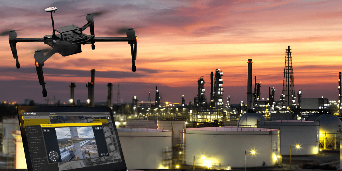 Drone flying over an industrial area with oil storage tanks and a sunset sky