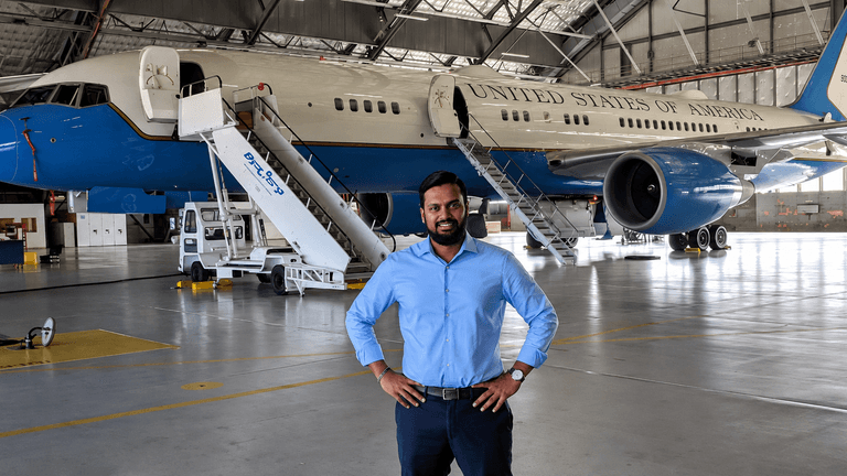 Alam Anthony Jamal standing inside an aircraft hangar in front of a United States government aircraft.