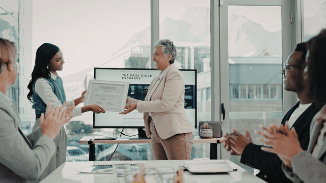 Employee receiving a workplace award certificate during an office recognition ceremony.