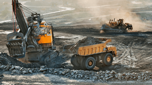 Large excavator loading rock into a haul truck at an open-pit mining operation.