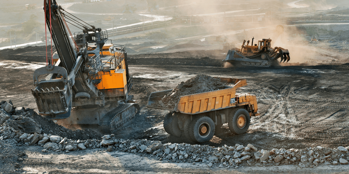 Large excavator loading rock into a haul truck at an open-pit mining operation.
