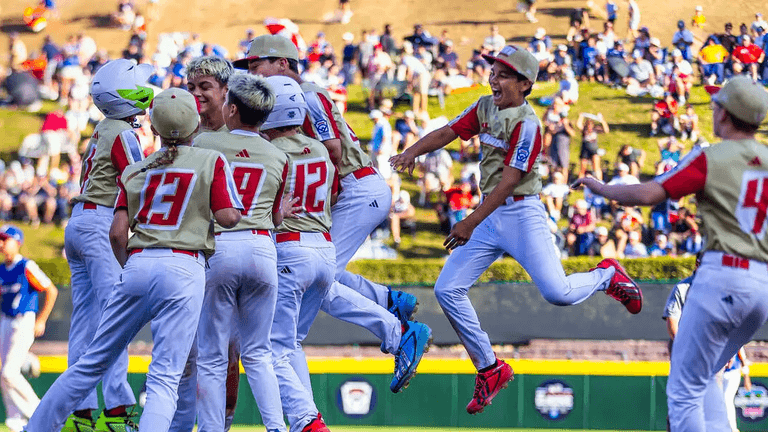 Young baseball players celebrating a victory on the field with fans in the background