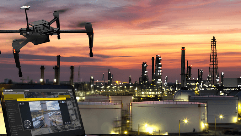 Drone flying over an industrial area with oil storage tanks and a sunset sky