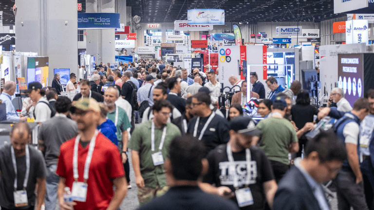Crowded exhibition hall filled with attendees and booths showcasing various products and services