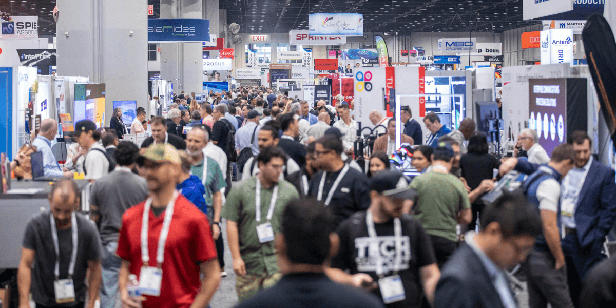Crowded exhibition hall filled with attendees and booths showcasing various products and services
