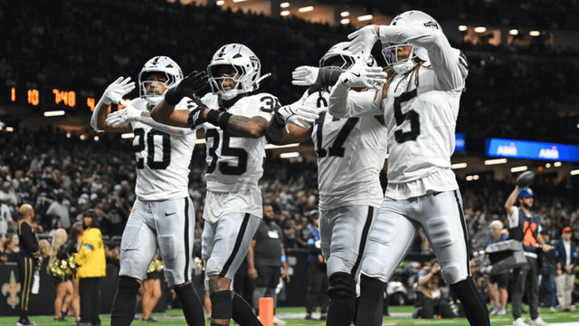 A group of football players celebrating a play in black and white uniforms