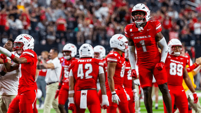 Football team celebrating a successful play, wearing red uniforms in a stadium
