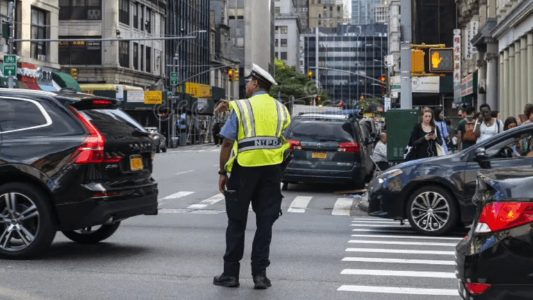 A police officer directing traffic at a busy city intersection with cars and pedestrians