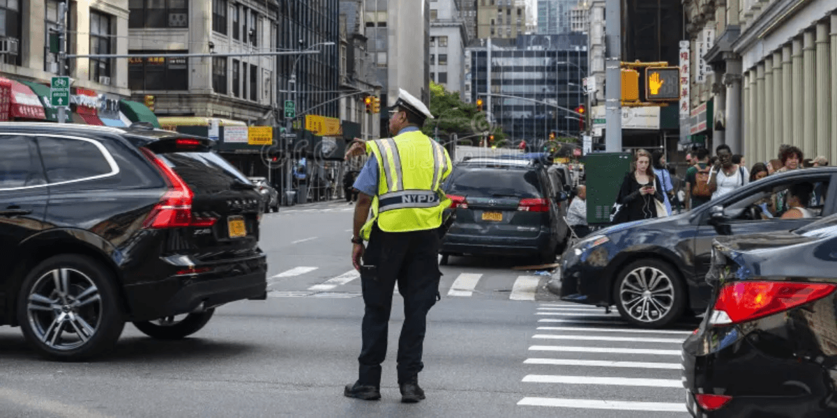 A police officer directing traffic at a busy city intersection with cars and pedestrians