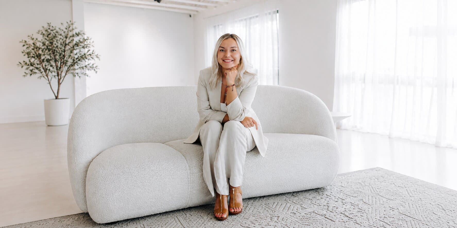 Josey Lesmeister seated on a white sofa in a bright studio.